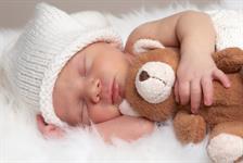 ein Baby, das mit einem Kuscheltier schläft